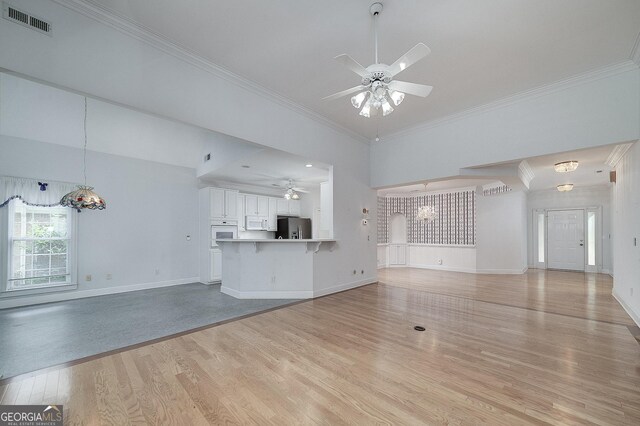 unfurnished living room with a high ceiling, light hardwood / wood-style flooring, ceiling fan, and ornamental molding