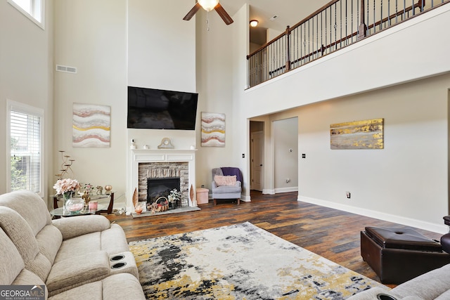 living room with ceiling fan, dark wood-type flooring, and a high ceiling