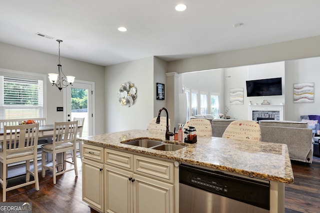 kitchen featuring sink, light stone counters, stainless steel dishwasher, a notable chandelier, and an island with sink