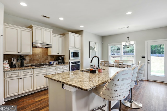 kitchen featuring a kitchen island with sink, sink, a chandelier, and appliances with stainless steel finishes