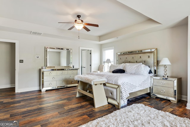 bedroom featuring a raised ceiling, ceiling fan, and dark wood-type flooring