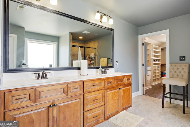 bathroom featuring tile patterned floors, a shower with door, and vanity