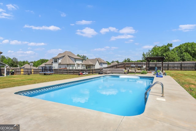 view of swimming pool featuring a lawn and a trampoline