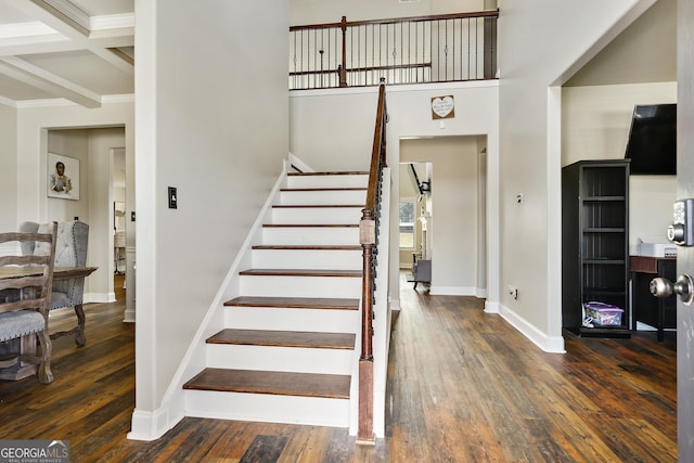 stairs featuring beam ceiling, hardwood / wood-style floors, and coffered ceiling