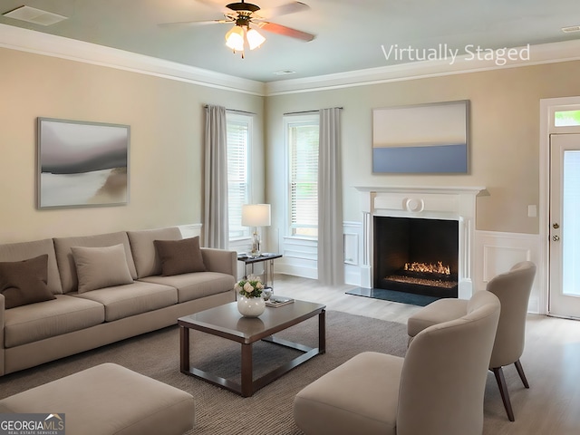 living room with ceiling fan, light wood-type flooring, and ornamental molding