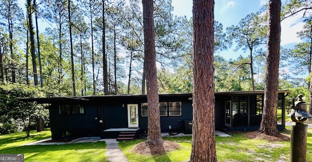 ranch-style house with a sunroom, central air condition unit, and a front lawn