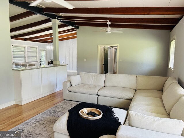 living room featuring lofted ceiling with beams, ceiling fan, and light wood-type flooring