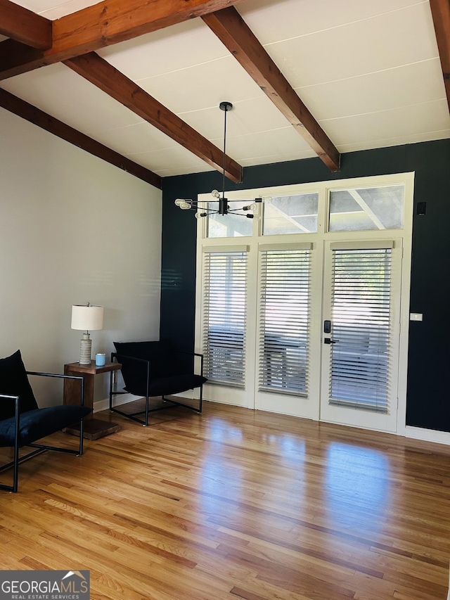 interior space with lofted ceiling with beams, a chandelier, and light hardwood / wood-style floors