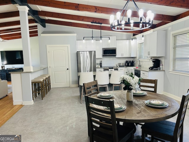 dining space with an inviting chandelier, light hardwood / wood-style flooring, vaulted ceiling with beams, and decorative columns