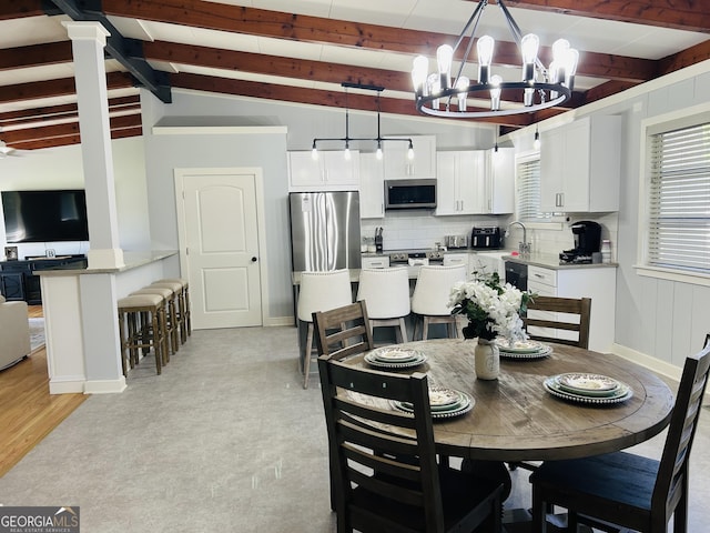 dining area featuring vaulted ceiling with beams, sink, and a notable chandelier