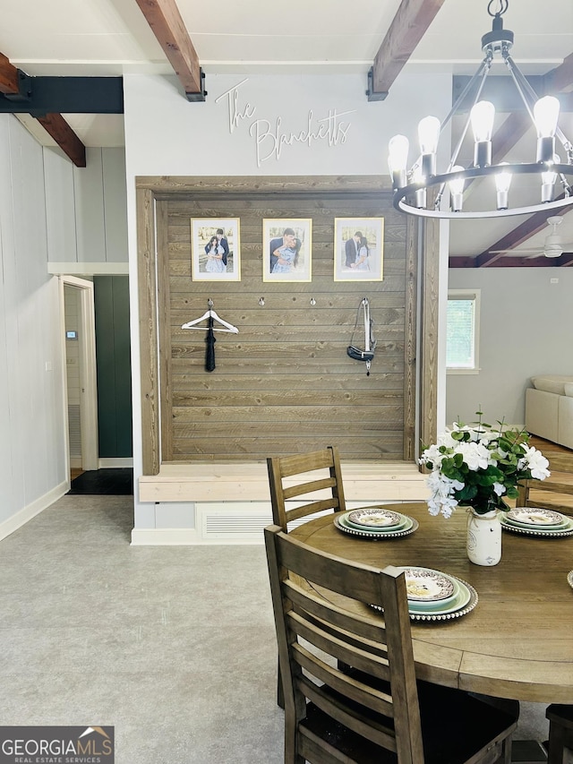 carpeted dining area featuring an inviting chandelier, beam ceiling, and wood walls