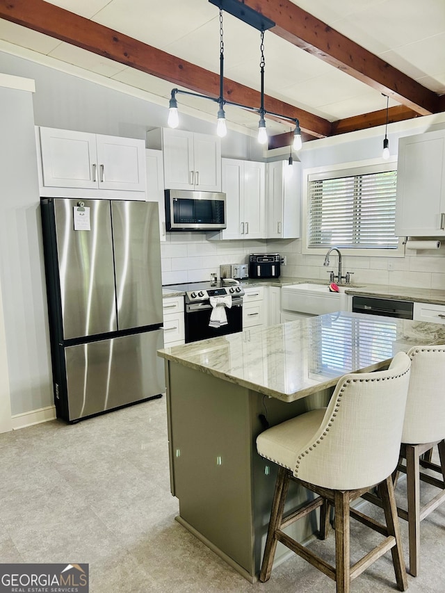 kitchen featuring white cabinetry, decorative light fixtures, stainless steel appliances, and a kitchen island