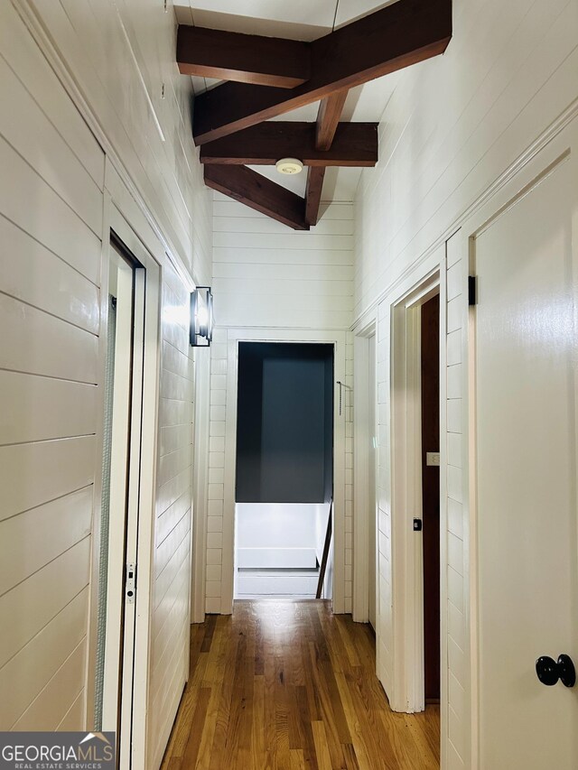 hall with wood-type flooring and vaulted ceiling with beams