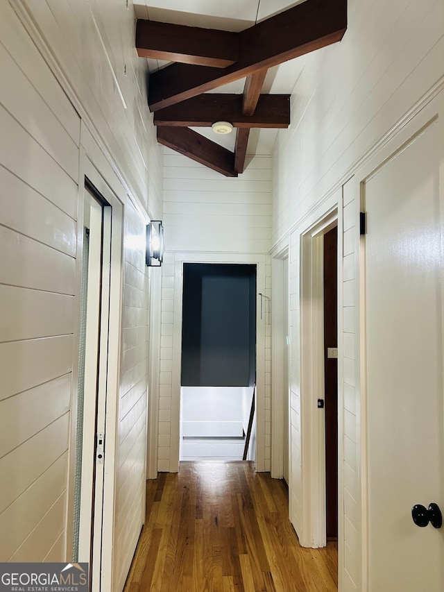 hallway featuring wood-type flooring, beam ceiling, and wood walls