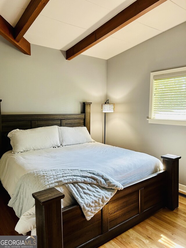 bedroom featuring light hardwood / wood-style floors and beam ceiling