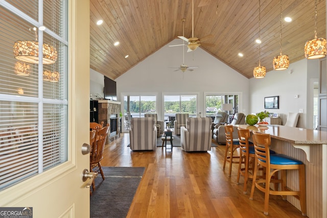 living room with ceiling fan, dark hardwood / wood-style floors, a tile fireplace, a towering ceiling, and wood ceiling