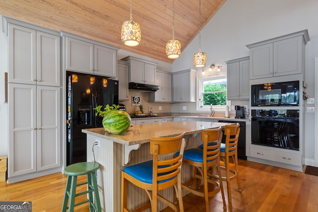 kitchen with black appliances, a center island, wood ceiling, decorative backsplash, and a breakfast bar