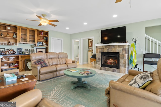 living room with ceiling fan and a fireplace