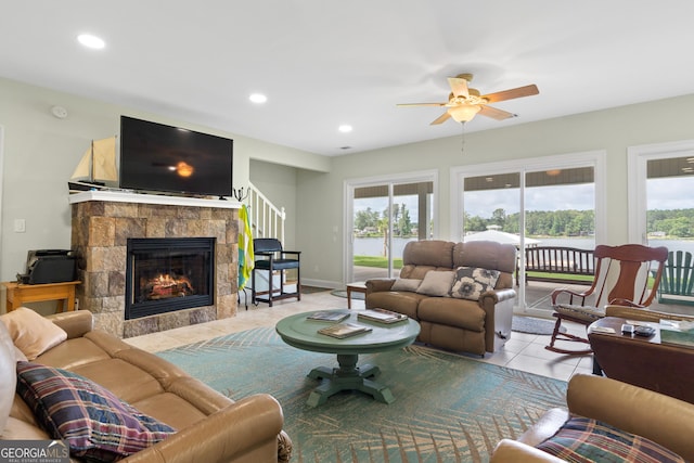 living room with ceiling fan, light tile patterned floors, and a stone fireplace