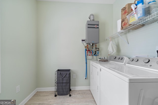 washroom with washing machine and dryer, tankless water heater, and light hardwood / wood-style flooring