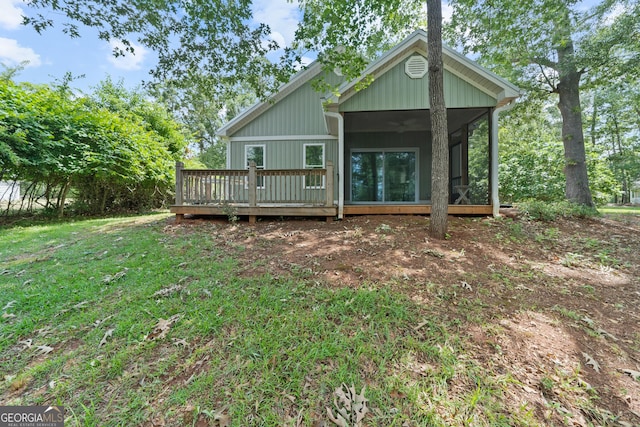 rear view of house with a wooden deck, a yard, and a sunroom