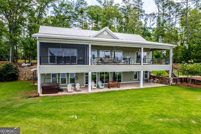 back of house featuring a yard, a hot tub, and a patio