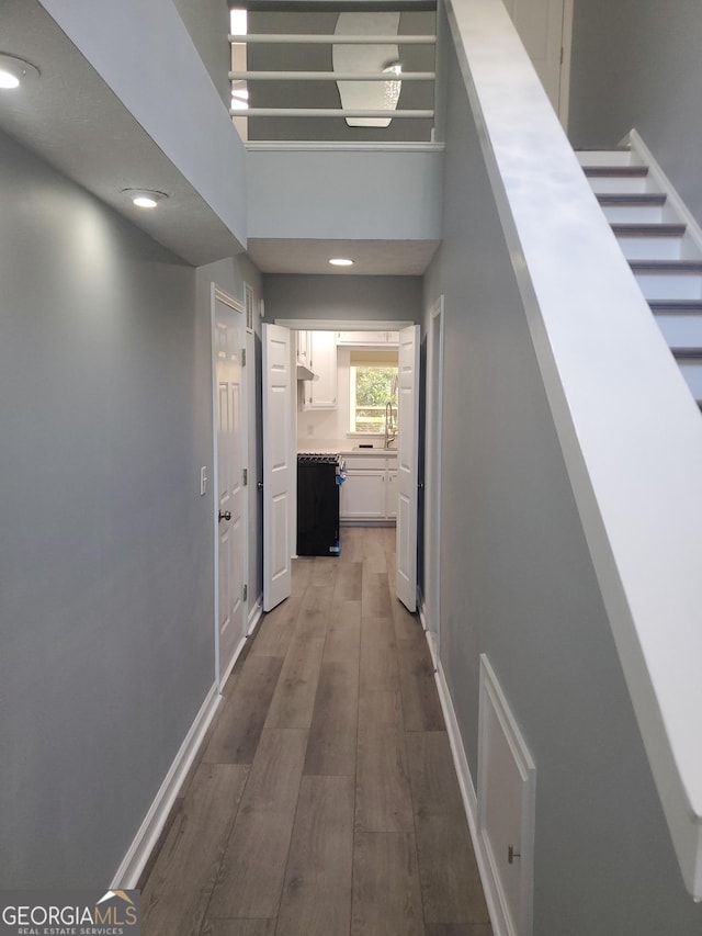 hall with hardwood / wood-style flooring, sink, and a high ceiling