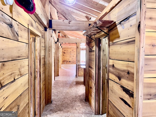 hall with wooden walls, beamed ceiling, and wood ceiling