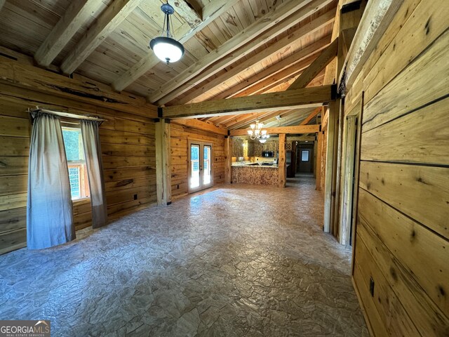 unfurnished living room with french doors, wood ceiling, a healthy amount of sunlight, an inviting chandelier, and vaulted ceiling with beams