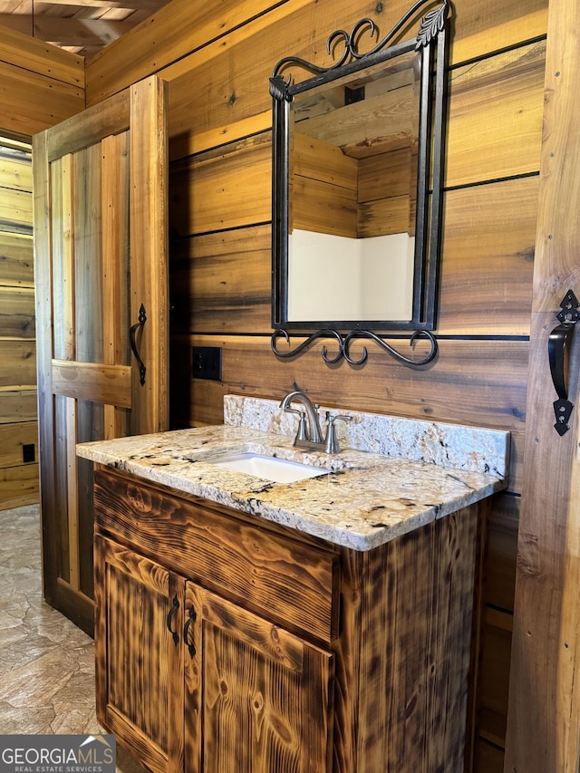 bathroom featuring vanity and wood walls