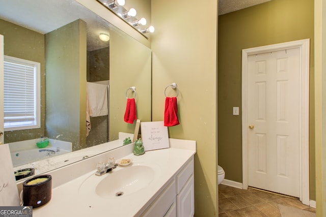 bathroom with a washtub, a textured ceiling, vanity, tile patterned flooring, and toilet