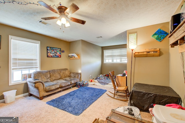 living room featuring light carpet, a textured ceiling, and ceiling fan