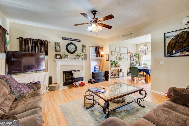 living room with a textured ceiling, ceiling fan with notable chandelier, and light hardwood / wood-style flooring