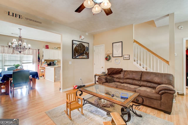 living room with a textured ceiling, light hardwood / wood-style flooring, and ceiling fan with notable chandelier