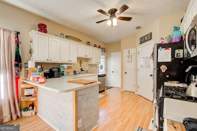 kitchen with kitchen peninsula, stainless steel appliances, ceiling fan, white cabinets, and light hardwood / wood-style floors