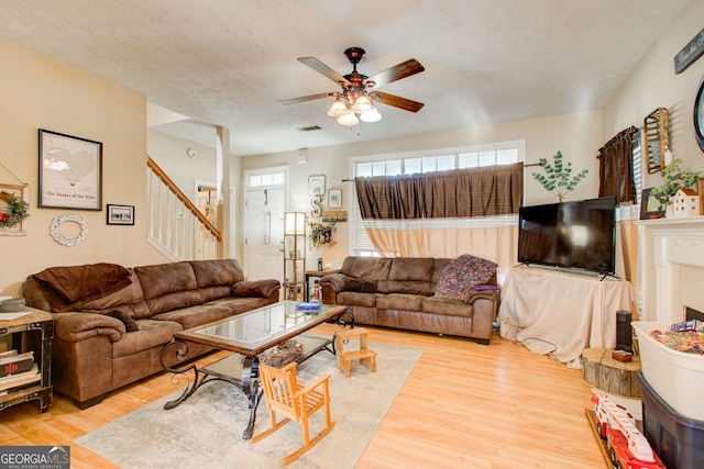 living room with a textured ceiling, light hardwood / wood-style flooring, and ceiling fan