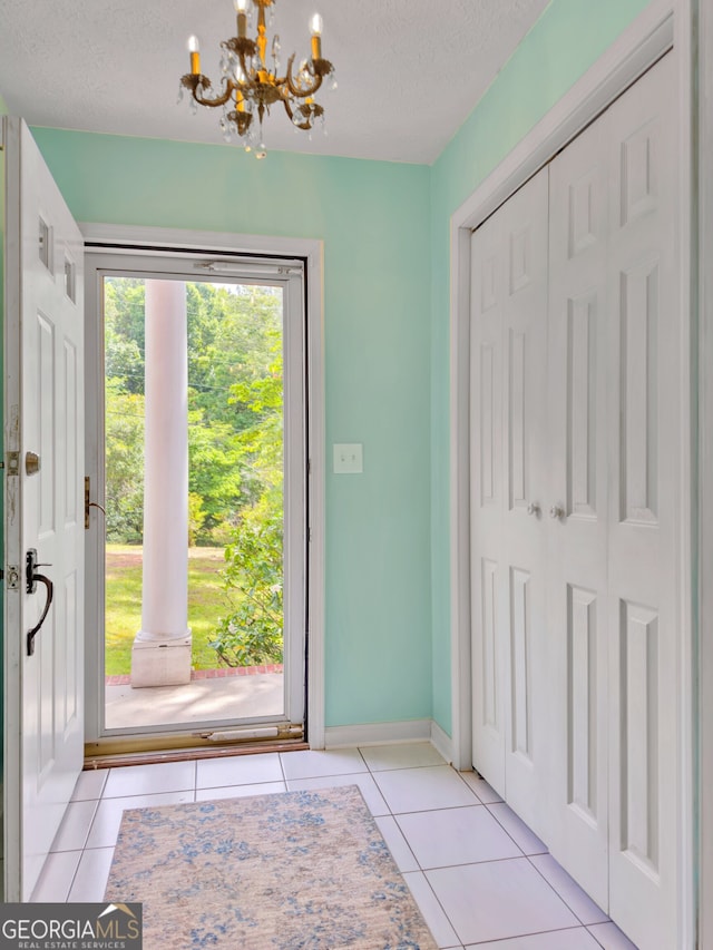 tiled entryway featuring an inviting chandelier and a textured ceiling