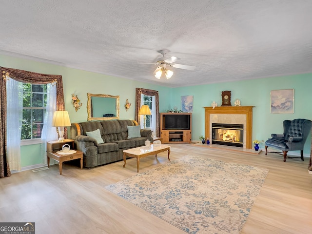 living room with a textured ceiling, ceiling fan, and light hardwood / wood-style floors