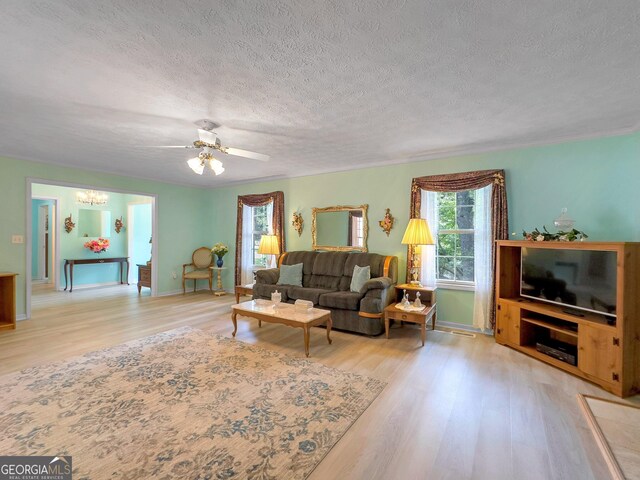 living room featuring light wood-type flooring, ceiling fan, and a textured ceiling