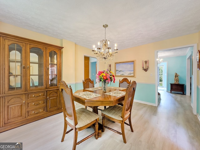 dining space with a chandelier, a textured ceiling, and light hardwood / wood-style floors