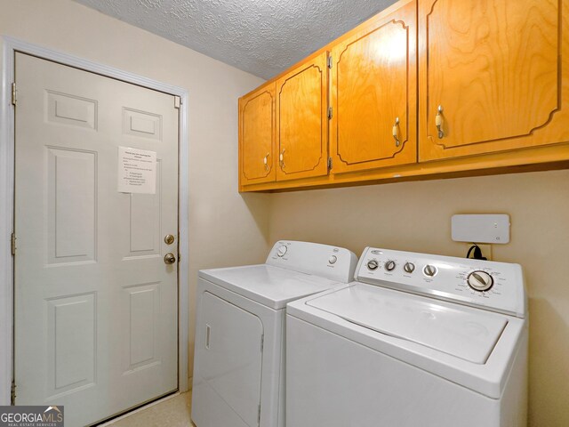 laundry room featuring cabinets, a textured ceiling, and washing machine and clothes dryer