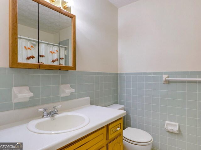 bathroom with a textured ceiling, backsplash, and tile walls