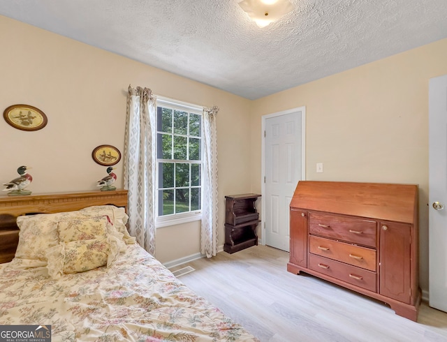 bedroom featuring a textured ceiling and light hardwood / wood-style flooring