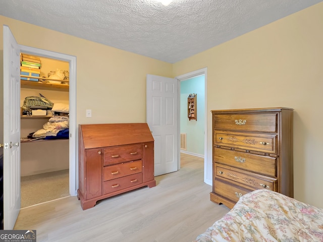 bedroom featuring a textured ceiling and light hardwood / wood-style flooring