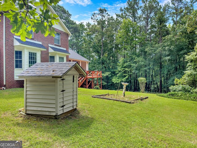 view of yard featuring a storage unit and a wooden deck