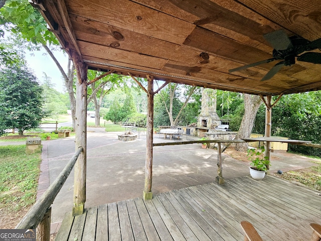 deck featuring exterior fireplace and ceiling fan