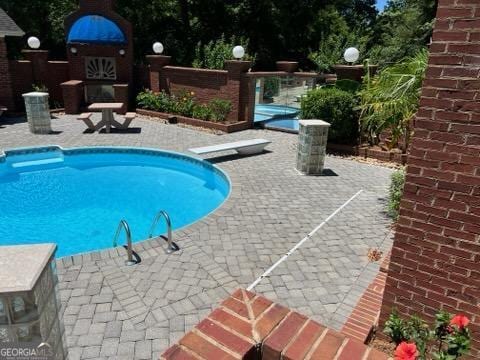 view of pool with a patio and a diving board