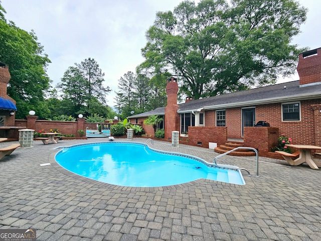 view of pool with a patio and a diving board