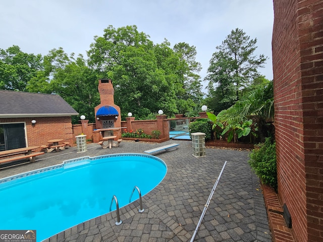 view of pool featuring a diving board and a patio area