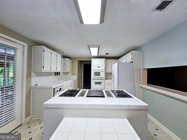 kitchen featuring white cabinetry, tile countertops, white appliances, and light tile floors